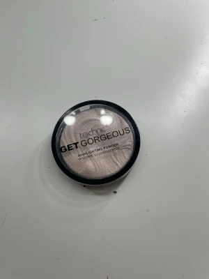 Technic Get Gorgeous highlighter - Technic Get Gorgeous highlighter i puderform med skimrande ljusrosa nyans. Kommer i en rund svart plastförpackning med transparent lock. Perfekt för att ge glow till ansiktet och framhäva kindbenen.