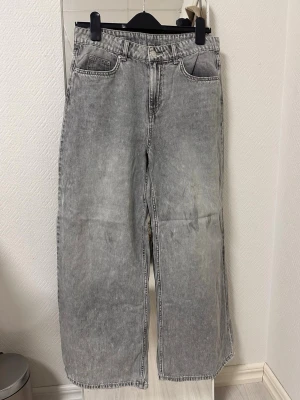 Gråa raka jeans med vintagekänsla - Säljer ett par gråa jeans med rak passform och klassisk femficksdesign. Jeansen har en tvättad look som ger en cool vintage vibe och är perfekta för en avslappnad stil. Materialet är denim och de har normal midja.