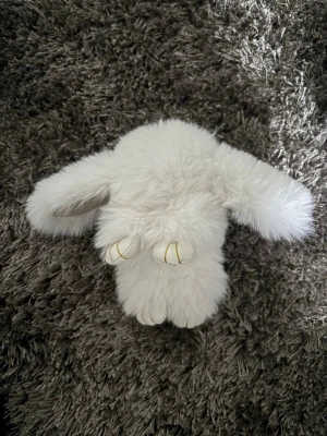 Vit fluffig kanin-nyckelring - Supersöt och fluffig vit kanin-nyckelring med långa öron och guldfärgade detaljer. Perfekt att hänga på väskan eller använda som accessoar. Tillverkad i mjuk fuskpäls och har en metallring för enkel fastsättning. Pris kan diskuteras.