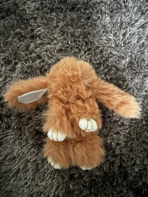 Brun fluffig kanin-nyckelring - Supersöt och fluffig kaninformad nyckelring i brun fuskpäls med vita tassar och öron med vit insida. Har en guldfärgad metallring för att enkelt fästa på väskan eller nycklarna. Perfekt accessoar för att ge din look en gullig touch. Pris kan diskuteras 