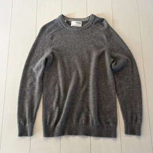 Grå rundhalsad tröja Selected Homme - Klassisk grå rundhalsad tröja från Selected Homme. Tröjan har ribbade muddar vid ärmslut, hals och nederkant. Tillverkad i mjukt material som passar perfekt till lager på lager och har en enkel, stilren look.