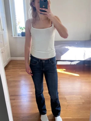 Mörkblå bootcut jeans - Snygga mörkblå bootcut jeans med klassisk femficksdesign och låg midja. Jeansen har en smal passform upptill och lätt utsvängda ben. Perfekta till en enkel topp eller hoodie. Materialet är troligtvis bomullsdenim med lite stretch för extra komfort. Säljer då de är för korta för mig.