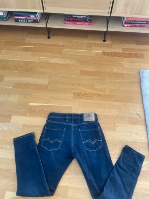 Mörkblå jeans från Replay - Snygga mörkblå jeans från Replay med klassisk femficksdesign och kontrastsömmar. Jeansen har raka ben och läderpatch med logga bak i midjan. Perfekta för en trendig och avslappnad stil.