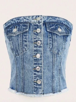 Jeanstopp med knappar och fickor - Snygg jeanstopp i ljusblå med knappar framtill och två bröstfickor. Toppen har bandeau-modell och smockad baksida för skön passform.