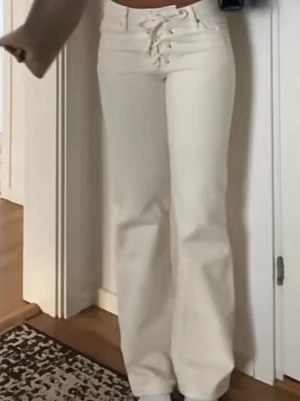 Vita raka jeans med snörning fram - Säljer ett par vita jeans med snygg snörning framtill i midjan. Använda 2 gånger!