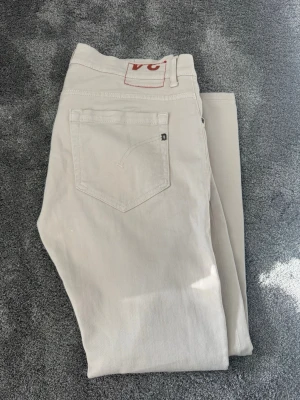 Dondup Beige - Snygga beiga jeans från Dondup modell George w34 (sitter som w33)  med klassisk femficksmodell och knappgylf. Jeansen har raka ben och är tillverkade i ett mjukt bomullstyg. Perfekta för en clean och stilren look. Endast provade och inte använda.