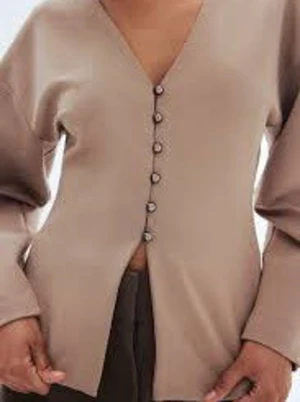Beige blus med v-ringning och knappar - Stilren beige blus med djup v-ringning och dekorativa knappar framtill. Blusen har lång ärm och en rak, något boxig passform. Tillverkad i ett slätt, vävt material som ger en modern look💞💞