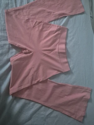 Rosa bootcut leggings - Säljer ett par rosa leggings med bootcut-ben. De har hög midja och är gjorda i ett mjukt, stretchigt material som sitter skönt på kroppen. Perfekta för en avslappnad och trendig look.