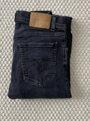 Svarta skinny jeans Tiger of Sweden - Snygga mörkblå skinny jeans från Tiger of Sweden med klassisk femficksdesign och läderpatch bak i midjan. Jeansen har smal passform och är tillverkade i stretchigt denim för en bekväm känsla.