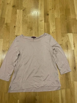 Indiska Beige topp med trekvartsärm stl M  - En stilren beige topp med rund halsringning och trekvartsärm. Toppen har en enkel design och är lätt att matcha till olika outfits. Perfekt för dig som gillar en clean och avslappnad look.