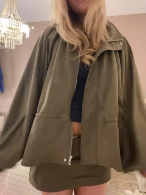 olivgrön jacka - Grön oversized jacka i storlek XS i nyskick Snygg och trendig modell med oversized passform, dragkedja framtill och justerbar midja. Mjuk och följsam känsla som passar perfekt till både vardag och kvällslook. Färgen är en mörk olivgrön ton.  Säljs eftersom den inte kommer till användning 🤍 nypris 696kr