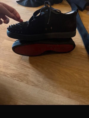 Svarta sneakers med nitar och röd sula - Säljer ett par svarta sneakers från Christian Louboutin då de inte kommer till användning och skulle gärna vilja byta till 37,38  