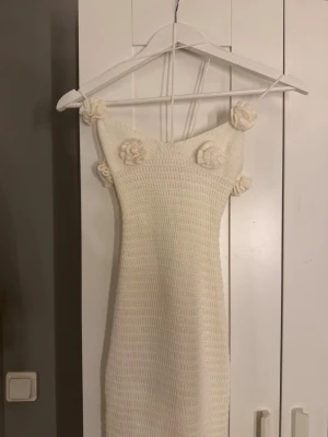 Vit virkad strandklänning  -  Helt ny Supersöt långklänning i virkad stil med smala axelband och virkade blommor som detaljer. Klänningen är figurnära och har en mjuk, bohemisk känsla. Perfekt för sommarens alla tillfällen och ger en romantisk vibe. Funkar till stranden eller nu till sommaren. Den är köpt på en marknad utomlands men har aldrig kommit till användning. Fanns ingen prislapp på. 