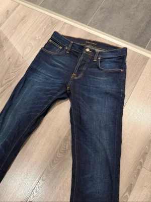 Nudie Jeans Grim Tim  - Säljer dessa tvärfeta grim Tim jeans med skit snygg färg storlek W30 L32 knappen på framsidan är lagad men inga hål defekter eller något liknande. Skriv gärna vid intresse 