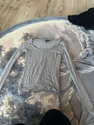 Beige långärmad topp - En enkel och stilren beige långärmad topp med rund halsringning. Tillverkad i ett mjukt och tunt material som känns skönt mot huden. Perfekt att matcha med jeans eller kjol för en clean look.