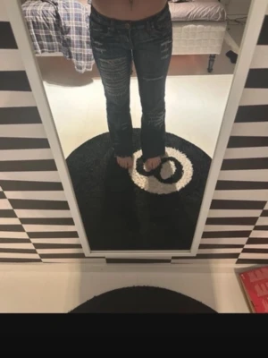 Mörkblå bootcut jeans med slitningar - Säljer ett par mörkblå bootcut jeans med snygga slitningar och tvättade detaljer. Jeansen har låg midja och klassisk femficksmodell. Perfekta för dig som gillar en avslappnad men trendig stil.