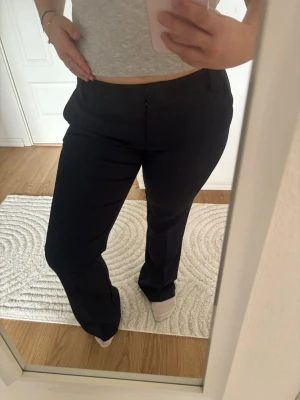 Mörkblå kostymbyxor från Bik Bok - Snygga mörkblå kostymbyxor från Bik Bok med klassisk rak passform och diskreta fickor. Byxorna har hällor för skärp och stängs med dragkedja och knapp. Perfekta för en stilren look och lätta att matcha med olika toppar.