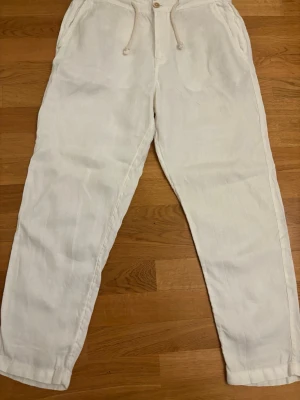 Vita linnebyxor från zara  - Snygga vita linnebyxor med avslappnad passform och dragsko i midjan. Byxorna har sidfickor fram och två bakfickor med knapp. Perfekta för en chill och stilren look. Tillverkade i luftigt linne som passar bra till varma dagar.
