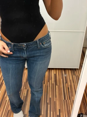 Bootcut jeans med låg midja - Snygga blå bootcut jeans med låg midja och klassiska fem fickor. Jeansen har en lätt tvättad look och sitter tajt upptill med utsvängda ben. Perfekta för en trendig och avslappnad stil.