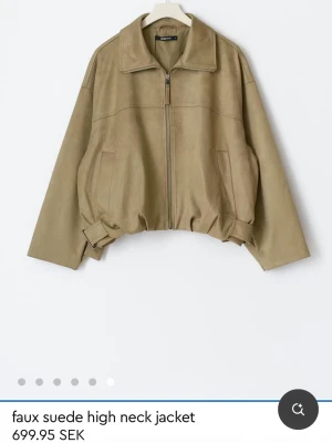 Beige faux mockajacka med dragkedja - Slutsåld på hemsidan❣️                                    Aldrig använd, lappen är kvar!                           Trendig olive/beigeaktig jacka i faux mocka från Ginatricot med hög krage, dragkedja framtill och justerbara detaljer i midjan. Jackan har en loose passform och långa ärmar, perfekt för lager-på-lager-stil.