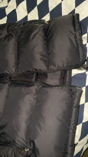 Svart quiltad dunväst Moncler - Västen är snygg och har blivit använden 5 gånger storleken är 1 (S) i monclet skriver man storlekar i siffror och det bevisar hur bra kopia den är det är en A kopia den första och bästa det ända som saknas med denna västen är att den inte är ute från själva affären.   Ja kan ör bra för våren och lite vintern fast skulle inte rekommenderat i sommar för den är väldigt varm. Det kommer också med kvittot från själva monclet affären 