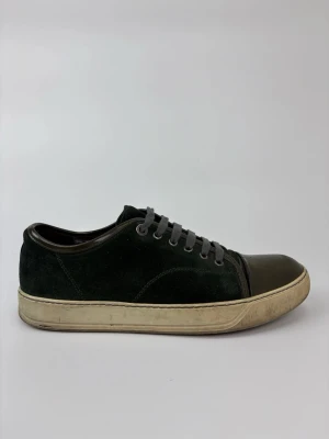 Svarta Lanvin sneakers med mocka och gummitå - Stilrena svarta sneakers i mocka med grå snörning och tåparti i mörkgrönt gummi. Yttersulan är beige och har en klassisk, låg profil. Perfekta för dig som gillar en clean och urban look.