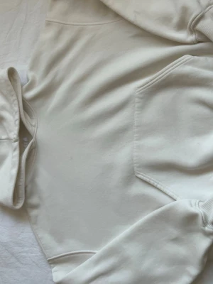 Vit hoodie från Gina Tricot - Säljer en stilren vit hoodie från Gina Tricot, kollektionen Elevated Basics. Hoodien har huva, magficka och ribbade muddar vid ärmslut och nederkant. Perfekt för en avslappnad och trendig look. Materialet är mjukt och skönt mot huden.