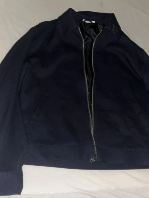 Svart bomberjacka från Zara - Klassisk svart bomberjacka från Zara med rak passform och hel dragkedja framtill. Jackan har två snedställda fickor och en stilren krage. Perfekt för dig som gillar en enkel men snygg look.