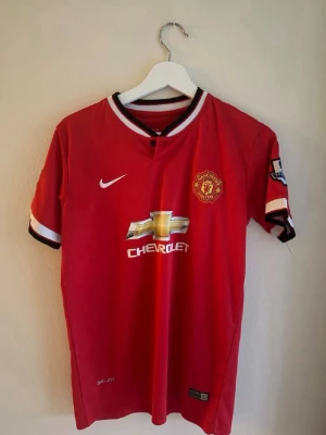 Manchester United Di Maria matchtröja - Röd Manchester United matchtröja från Nike med Di Maria och nummer 7 på ryggen. Tröjan har klubbmärke, Premier League-märke på ärmarna och Chevrolet-logga på bröstet. Tillverkad i lätt och ventilerande Dri-FIT-material, perfekt för fotbollsträning eller match.