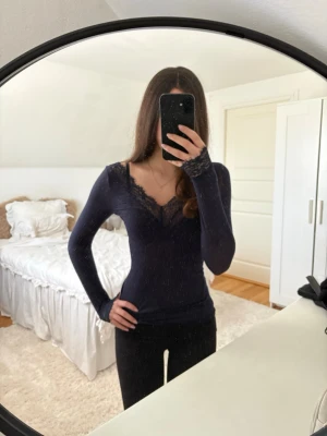 Mörkblå intimissimi topp med spets !OBS fast pris!  - Säljer en mörkblå långärmad topp med v-ringning och fina spetsdetaljer vid halsringningen och armkanten. Toppen har en slim passform och är perfekt för dig som gillar en stilren men ändå feminin look. Det igensydda märket på tröjan syns inte tydligt då det är på underarmen!!