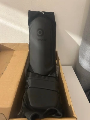 Svarta benskydd från Chokem - Säljer ett par svarta benskydd från Chokem, perfekta för kampsport eller träning. De är tillverkade i slitstarkt material och har vaddering för extra skydd. Sitter bekvämt på benet och ger bra stöd under sparring eller träning. Säljer på grund av att jag bytte till muaythai innan mitt paket levererades, benskyddet är helt nytt och oanvända.