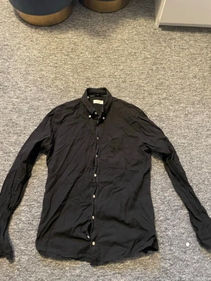 Svart skjorta från Eton, slim fit - Snygg svart linneskjorta från Eton i slim fit-modell. Skjortan har klassisk krage, långa ärmar och knappar framtill. Perfekt för dig som gillar stilrena plagg med en modern passform.