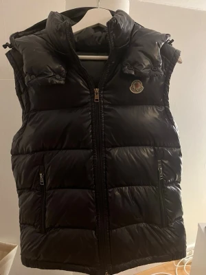 Svart dunväst från Moncler - Moncler Vest, skick 8/10, storlek M passar M/L.) Pris 5800kr )Moncler Cardigan Vit, skick 9/10, Storlek XL passar L pris 5500kr )