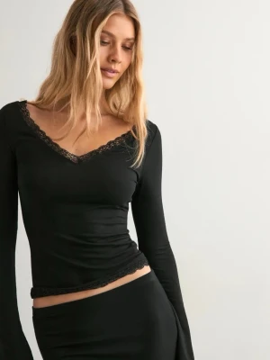 Spets tröja - Svart långärmad topp med v-ringning och fina spetsdetaljer vid halsringning och nederkant. Toppens material är stretchigt och sitter figurnära, perfekt för en stilren look.