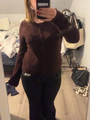 Vinröd fluffig kofta med knappar - Mysig vinröd kofta med fluffig textur och knäppning framtill. Långärmad modell med avslappnad passform, perfekt för lager på lager. Passar dig som gillar en enkel men ändå trendig stil.