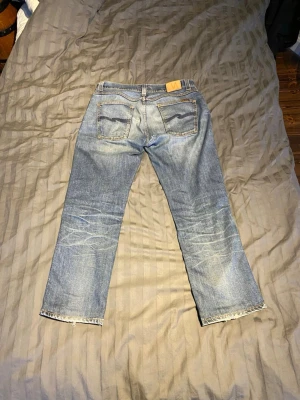 Blå Nudie jeans straight bootcut - Nudie jeans modell slimjim.  Pris 699. En modell med bootcut som lägger sig väldigt najs över skon. Dessa har blivit omsydda i längd i butik och motsvarar numera ca L31-L32. Storlekslappen säger w36 i midjemått men de sitter i själva verket mer som en w33a. Jag har kunnat haft dom utan problem och jag bär vanligtvis en w31/L32. En lagning som även gjorts i butiken på undersidan av byxorna men annars i gott skick utan skavanker. Skulle det vara något så är det bara att skriva!!