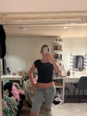 Svart croppad topp med öppen rygg - Snygg svart croppad topp med korta ärmar och öppen rygg. Toppen har en tight passform och är perfekt för att skapa en trendig look. Enkel och stilren design som passar till många outfits.