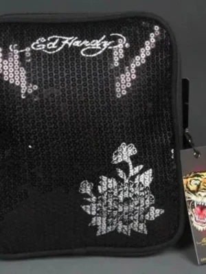 Svart axelväska med paljetter Ed Hardy - Snygg svart axelväska/messengerväska från Ed Hardy med glittrande paljetter på framsidan och vit blommig detalj. Väskan har justerbar axelrem och dragkedja baktill. Får plats med t.ex. en liten iPad. 