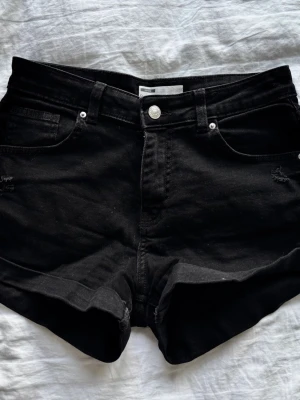 Svarta denimshorts med fem fickor - Svarta jeansshorts i klassisk femficksmodell med knapp och dragkedja framtill. Shortsen har en rak passform och är tillverkade i bomull. Perfekta för en avslappnad och stilren look.