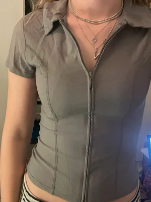 Tight kostym topp - Säljer en grå tight kostymkiknande topp som går att ha med eller uppdragen. Använd ett fåtal gånger och har inga fläckar! Skriv om du vill diskutera pris! 