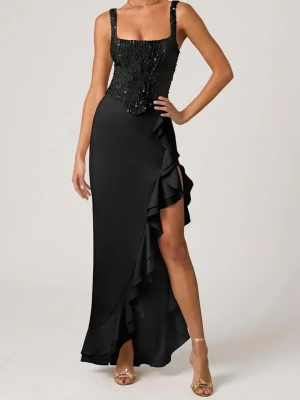 Svart långklänning med volang och paljetter - Supersnygg svart långklänning med smala axelband, glittrig paljettliv och volangdetalj längs sidan. Klänningen har en slits framtill och figurnära passform som framhäver siluetten. Perfekt för dig som vill sticka ut med en elegant look.