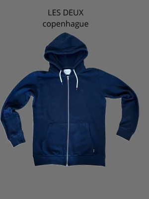 Hoodie Les Deux - Säljer en mörkblå hoodie från Les Delux. Tröjan är i utmärkt skick, inga defekter. Tröjan är i storlek S, men skulle säga att den har lite större passfrorm. Han på bilden är 185 och väger ca 70 kilo. Om ni har mer frågor eller funderingar är de bara att skriva:).      