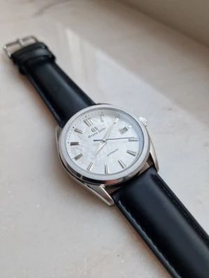 Seiko mod (Grand seiko) - Säljer en elegant Seiko mod med en boett på 40mm som har en stilren borstad och polerad finish. Uret har en vit GS tavla med textur och en blå sekundvisare för kontrast. Uret drivs av seikos automatiska nh35