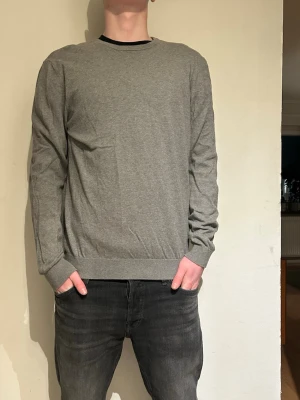 Grå stickad tröja - En enkel och stilren grå tröja med rund halsringning och långa ärmar. Tröjan är från matinique skick 8/10 inga defekter