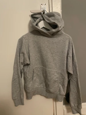 Grå hoodie från Rodebjer - Snygg grå hoodie från Rodebjer med klassisk huva och stor magficka. Tillverkad i mjukt sweatshirtmaterial som känns skönt mot huden. Perfekt för en avslappnad och stilren look. Ribbade muddar vid ärmslut och nederkant för extra komfort.