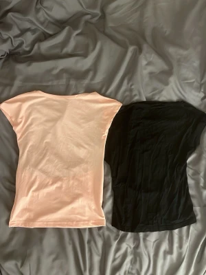 Två basic toppar i svart och ljusrosa - Säljer två enkla toppar i svart och ljusrosa. Båda har rund halsringning, ärmlös design och rak passform. Perfekta att matcha till jeans eller kjol. Materialet känns mjukt och stretchigt, troligen bomull eller polyester. Svart topp: söm lite nött men inget som märks! Rosa: kan finnas nån skavank ja missat💕