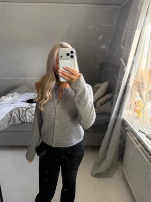 Grå mjuk kofta med knappar - Säljer en enkel och fin grå kofta med knäppning framtill. jätteskönt material , har långa ärmar och en rak passform som passar perfekt till alla möjliga ourtfirts! kan både har den öppet med nåt plagg under eller helt ”stängd”!  