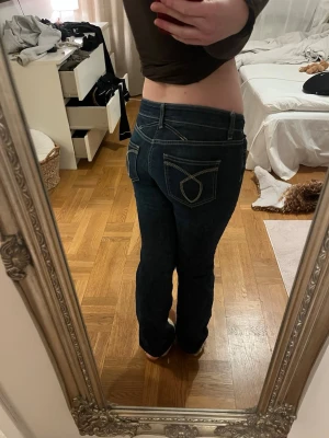 Mörkblå jeans med kontrastsömmar - Säljer ett par mörkblå jeans med snygga kontrastsömmar och detaljerade bakfickor. Jeansen har normal passform och klassisk femficksdesign. Perfekta till en avslappnad stil och passar till det mesta i garderoben.