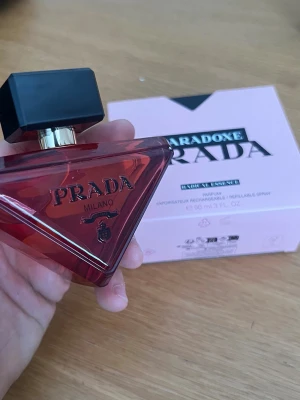 Prada Paradoxe Radical Essence parfym - Prada Paradoxe Radical Essence är en exklusiv parfym i en unik, triangelformad flaska med röd glas och svart, fyrkantig kork. Flaskan har eleganta gulddetaljer och tydlig Prada-logo. Perfekt för dig som vill ha en lyxig och modern doft.