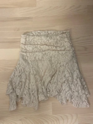 Krämvit/ljusgul spetskjol från Gina Tricot XS - Supersöt vit kortkjol från Gina Tricot i spets med volangdetaljer. Använd en gång 